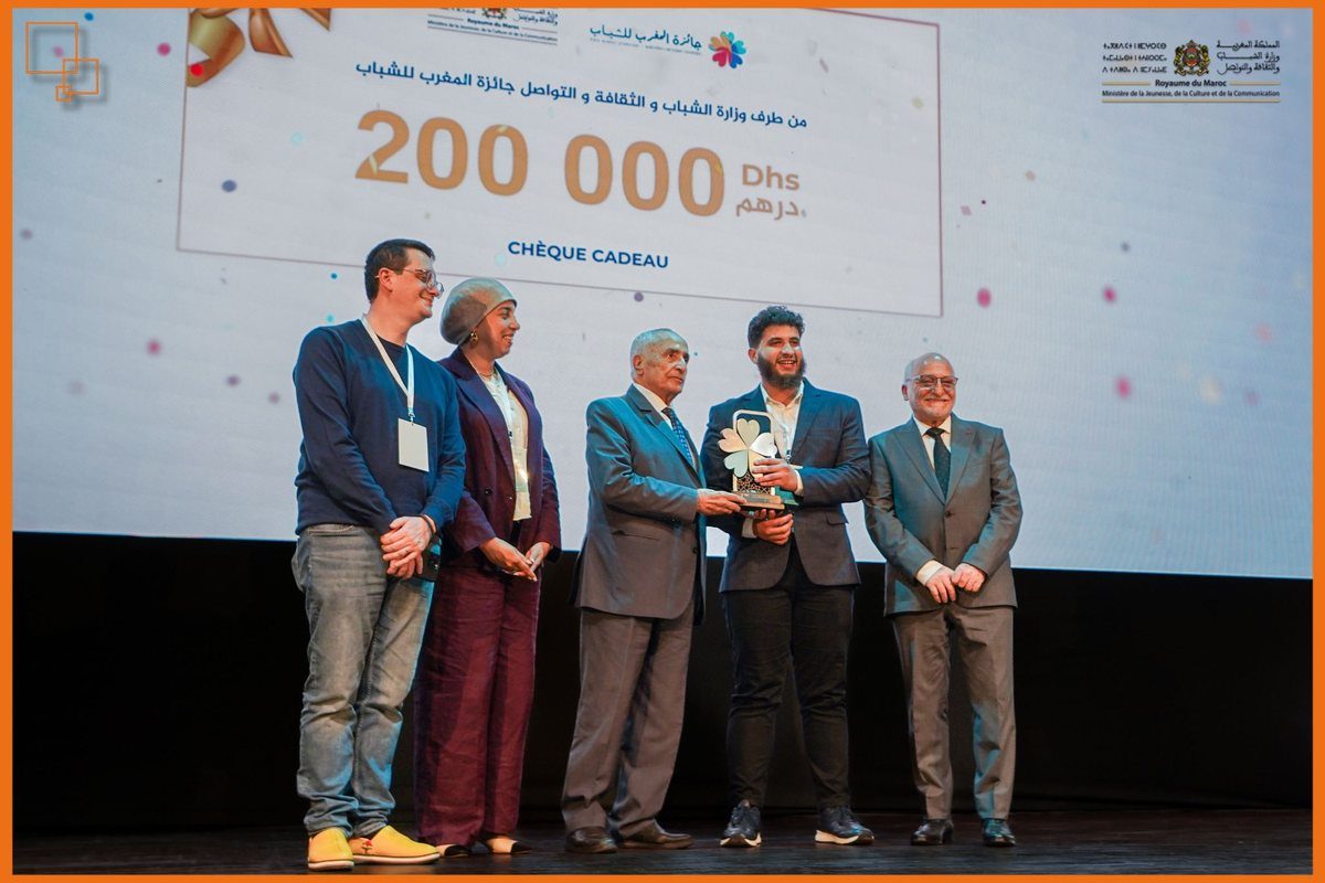 Hamza receiving the Prix Maroc Jeunesse trophy on stage, with the 200,000 dirham prize displayed behind.