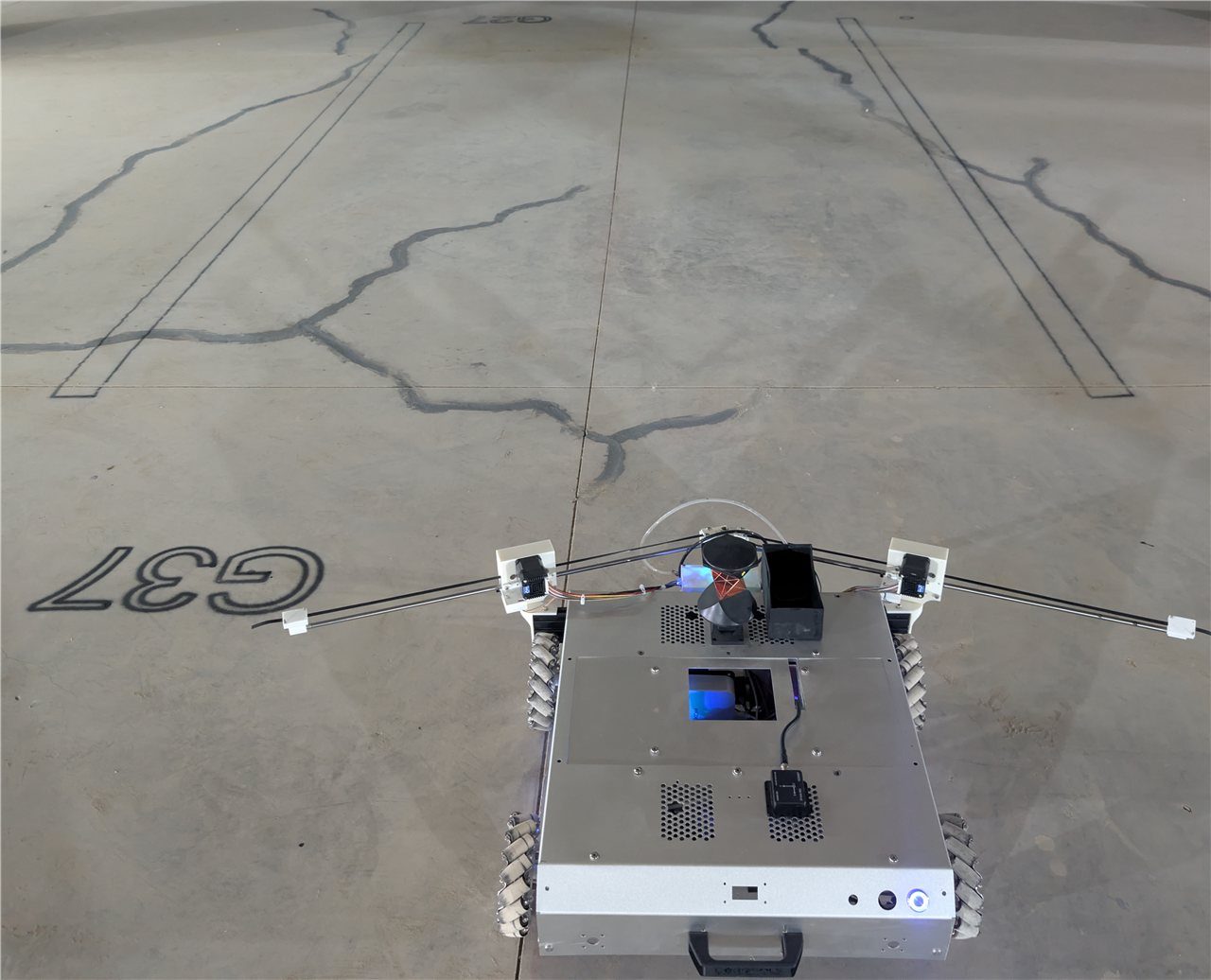The COROSOLS robot on real concrete beside crisp traced lines and a printed G37 label.
